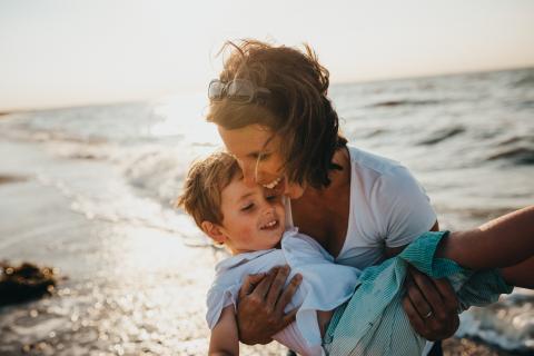 Mother holding young son in her arms at the beach